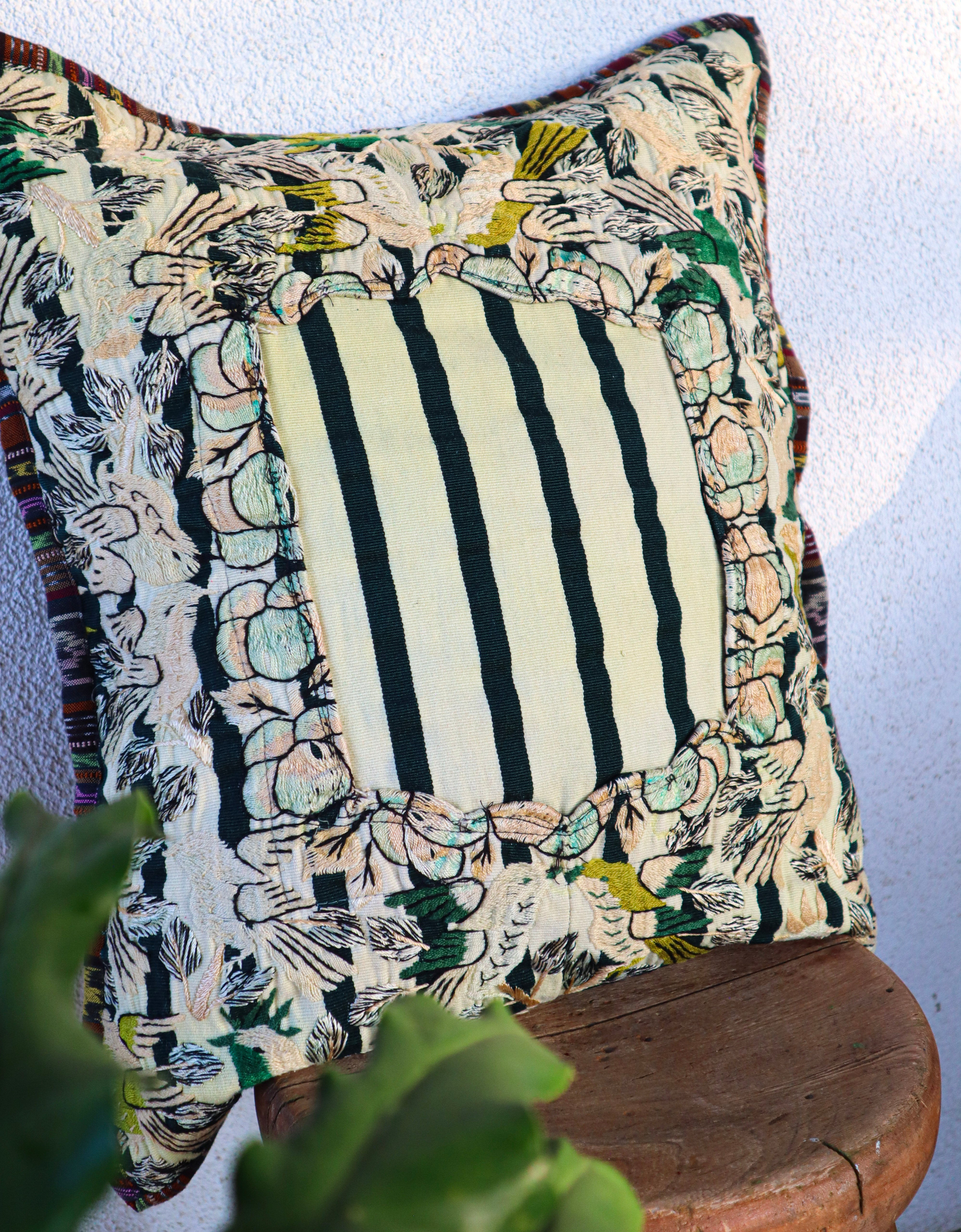 Decorative pillow with floral and striped patterns on a wooden chair.
