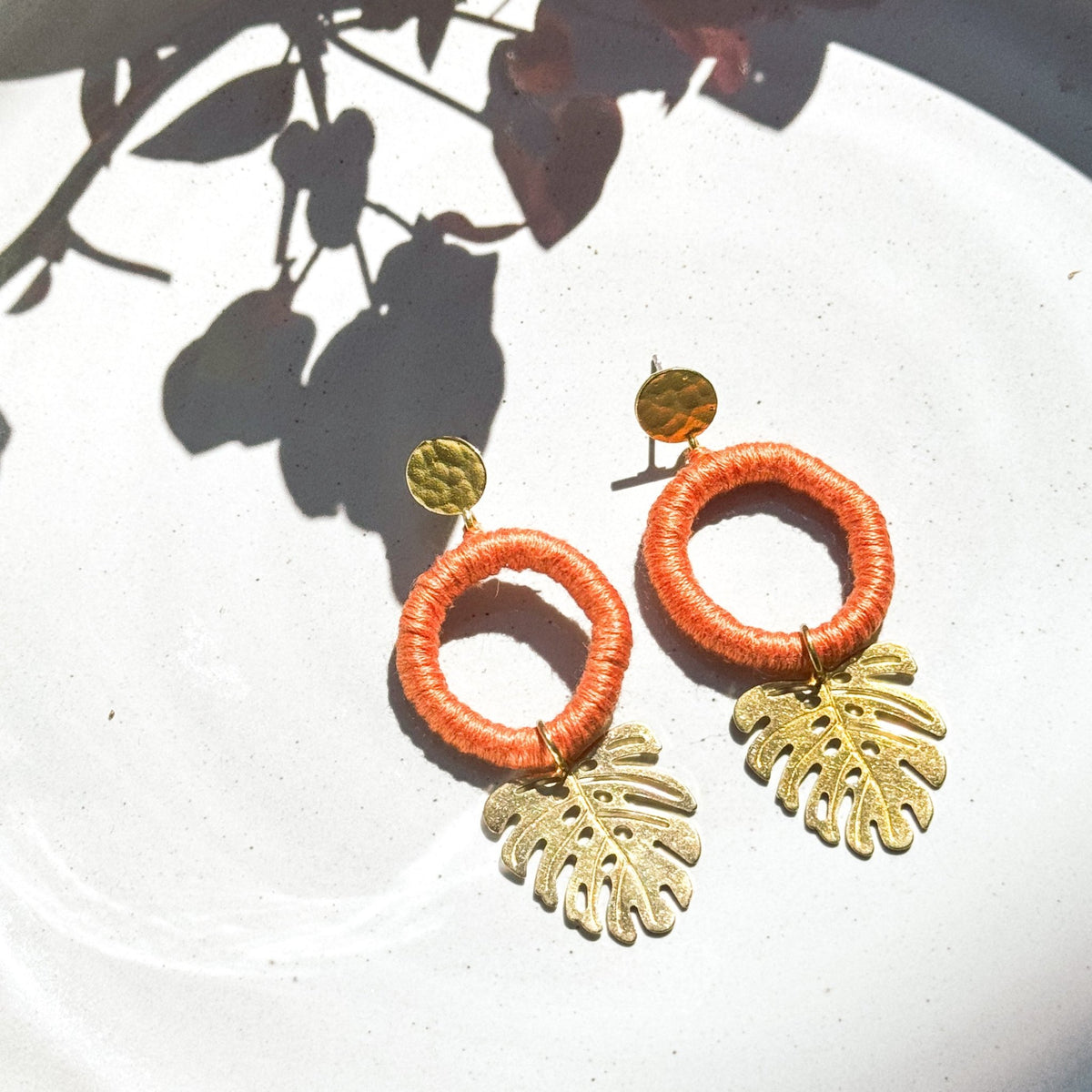 Soft apricot orange tropical leaf earrings with gold-tone leaf pendants, handmade in Guatemala