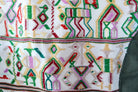 Angled back view of an olive-green vest showing its repurposed vintage Nebaj huipil panel