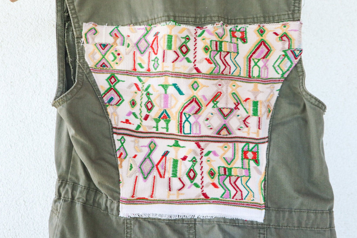 Angled back view of an olive-green vest showing its repurposed vintage Nebaj huipil panel