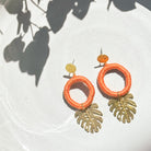 Soft apricot orange tropical leaf earrings with gold-tone leaf pendants, handmade in Guatemala