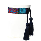 A handwoven Mayan belt with geometric patterns in blue, brown, and black, displayed on a mannequin.