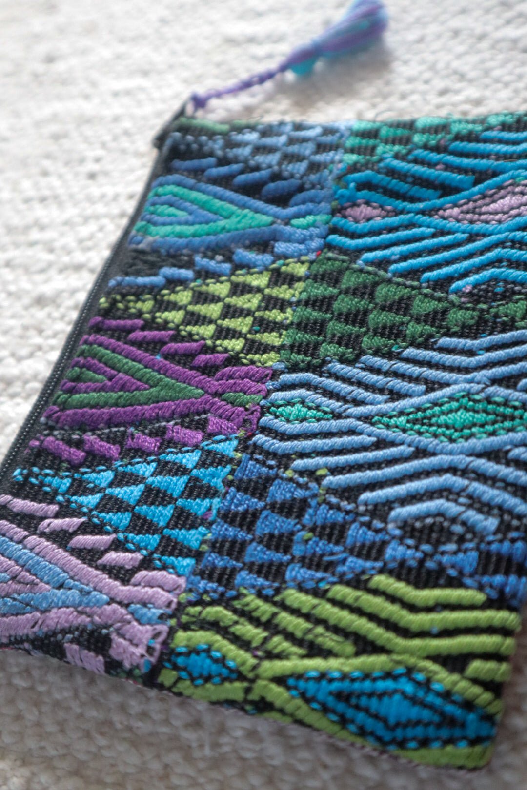Close-up of raised geometric patterns in blue, turquoise, green and purple on a Guatemalan huipil coin pouch.