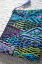 Close-up of raised geometric patterns in blue, turquoise, green and purple on a Guatemalan huipil coin pouch.
