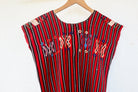 Close-up of colorful butterfly motifs and handwoven red, black, and white stripes on a vintage Chajul huipil