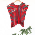 Close-up of colorful butterfly motifs and handwoven red, black, and white stripes on a vintage Chajul huipil